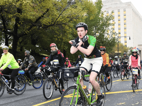 A cyclist crosses his arms in a BX gesture while riding with a large group during the 2018 Tour de Bronx on the Grand Concourse.