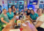 Group of women smiling together at a bar table.