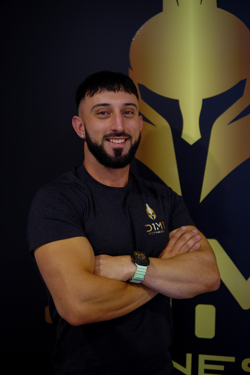 Dimitri Morogiannis, founder of D1M1 Fitness, in front of the gold spartan helmet wall