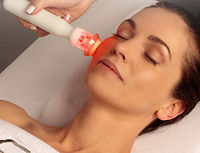 Photo of a femail having a CACI prep and glow beauty treatment on her face using a red CACI light device.