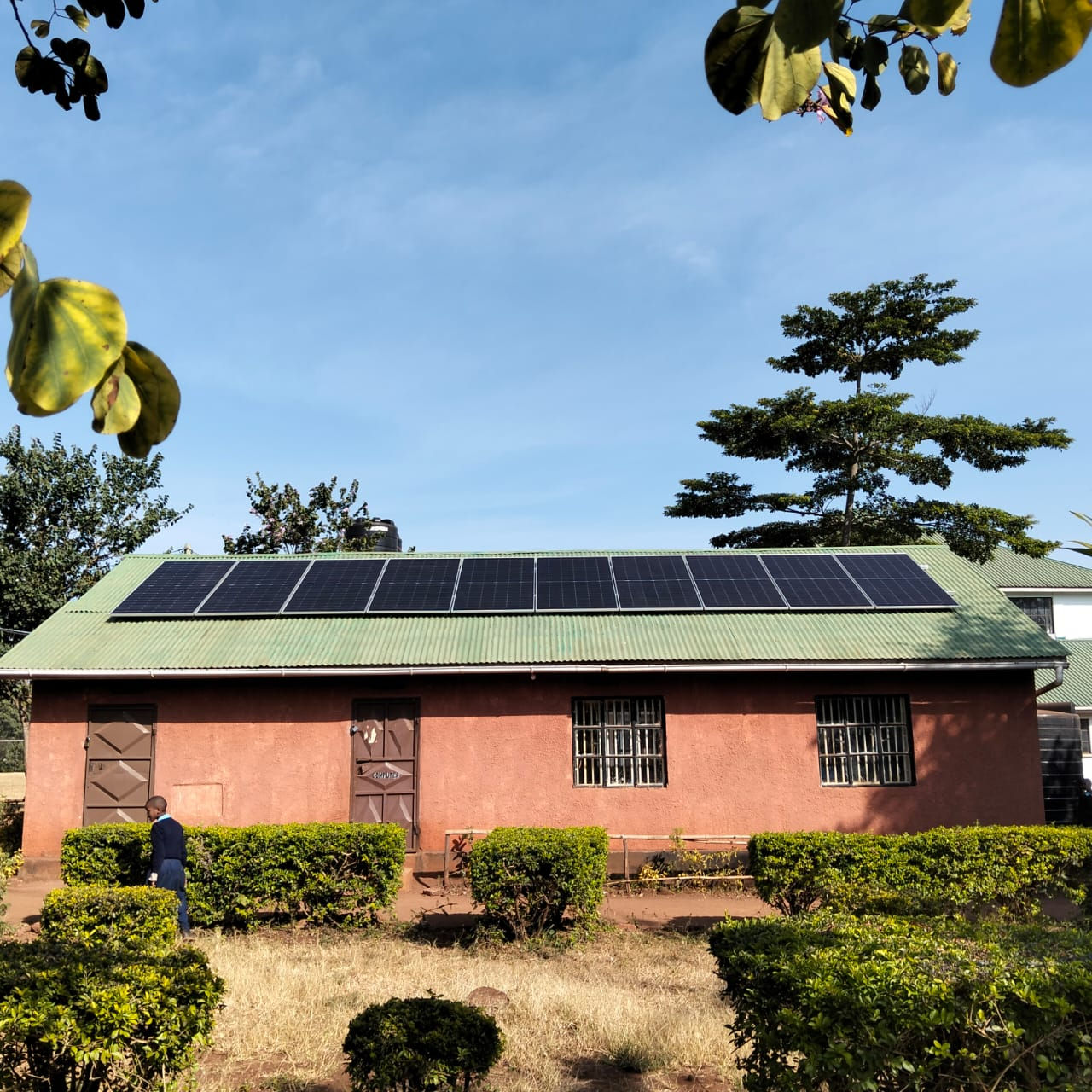 A red brick building with a green roof, and new solar pannels installed.