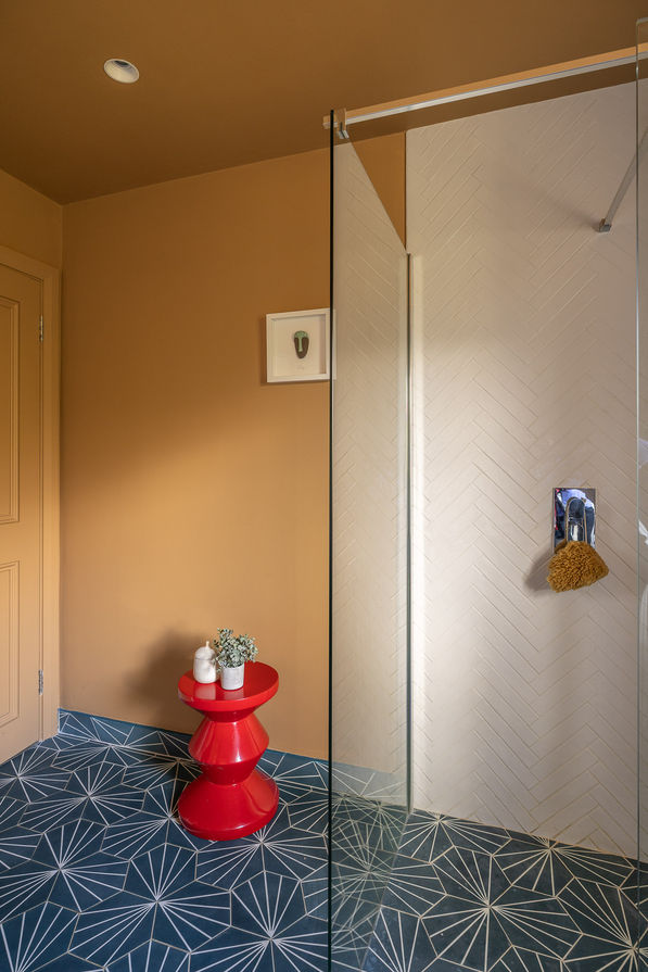 a bathroom with a red stool and a picture on the wall