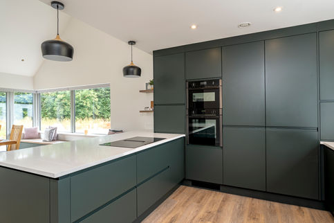 a kitchen with green cabinets and a stainless steel oven