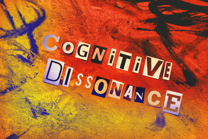 Text "Cognitive Dissonance" in cut-out letters on a vivid red, orange, and yellow textured background, conveying a bold, chaotic mood.