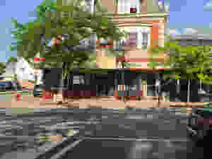 A car just leaving, a sunny day with the outside front of Vinny's Pizzeria