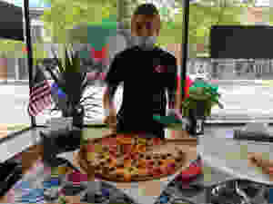Employee serving a pepperoni pizza slice