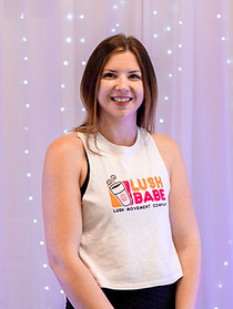 30 year old woman with brown hair pulled back. She is wearing a Lush Babe tank top. She is smiling and a dance teacher.