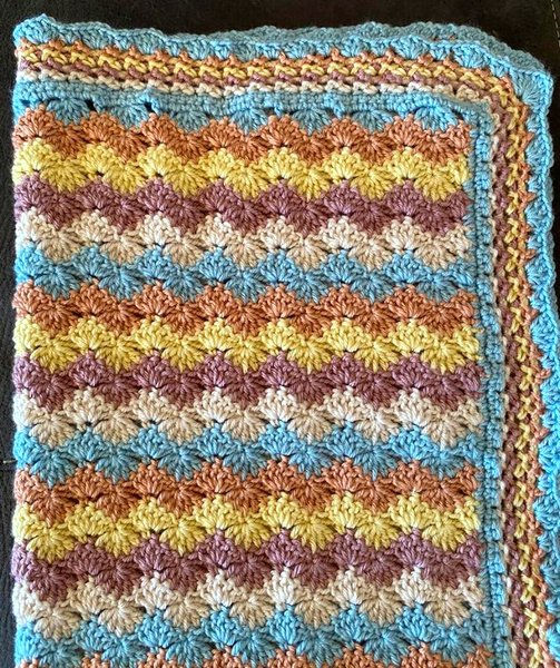 Chevron Shells Baby Crochet Rug Folded Up View in Purple, Yellow, Aqua and Cream