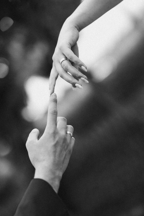 Hände von Braut und Bräutigam berühren sich, Ehering am Finger der Braut, Detailaufnahme in Schwarzweiß