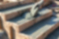 A gloved hand uses a trowel to spread wet concrete into the wooden frame of a staircase.jp