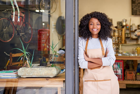 Portrait of a smiling young African American barista standing with her arms crossed at the