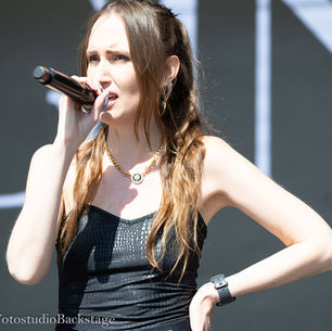 GINAxC holding a microphone, performing live on stage