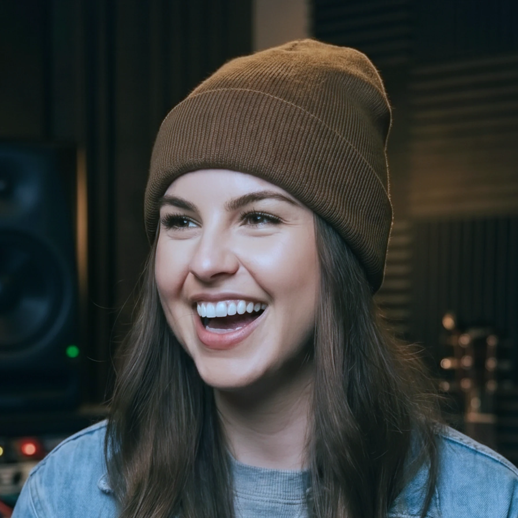 Power Producer mentee Emma Kay smiling, wearing a brown beanie hat, in a professional music studio.