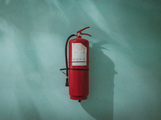 Red fire extinguisher on a green wall