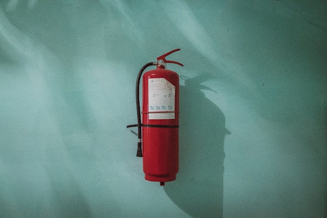 Red fire extinguisher on a green wall