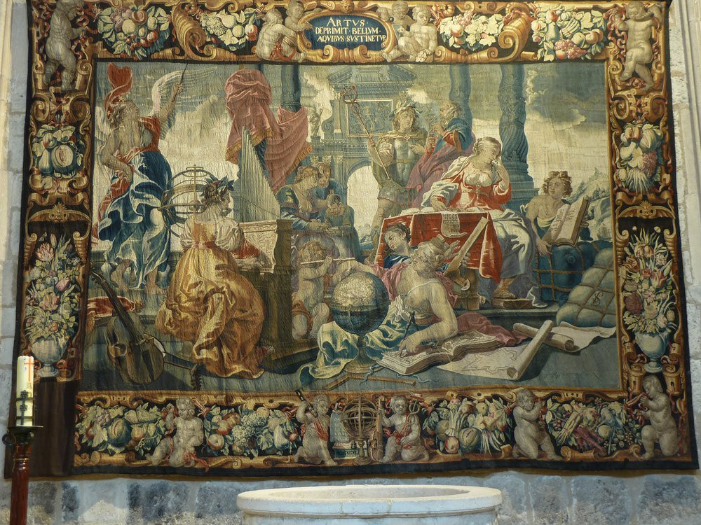 The Flemish tapestry hanging on the church wall with a missing pice on the bottom left hand corner
