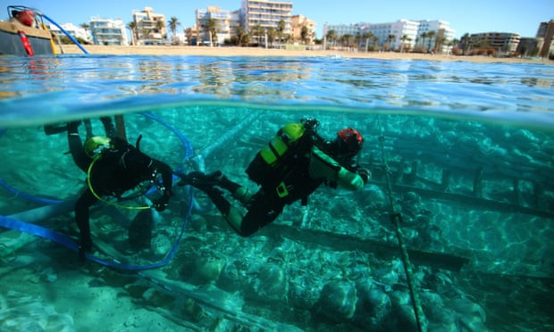 Two scuba divers exploring the wreck just below the surface of the sea