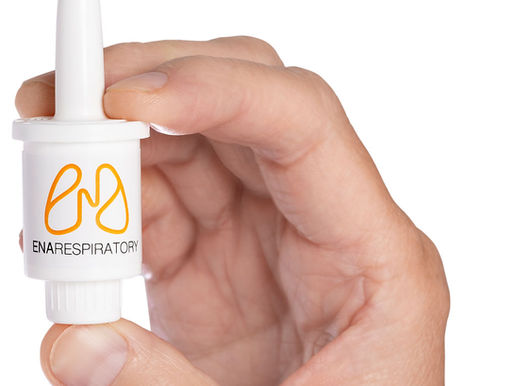 Someone's hand holding a small white tube of ENA Respiratory branded nasal spray