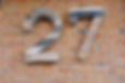 The number '27' painted on a brick wall