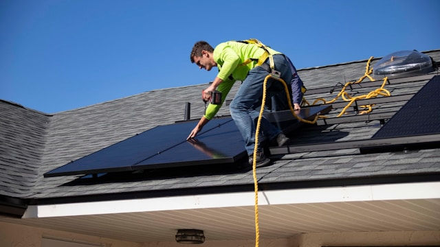 Man installing a solar panel on the roof of a home