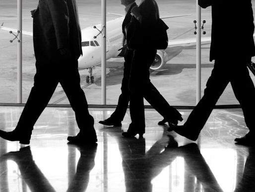 4 business men in suits walking towards their flight