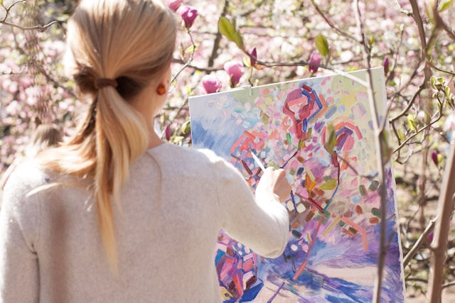 Woman painting a magnolia tree in her sunny garden