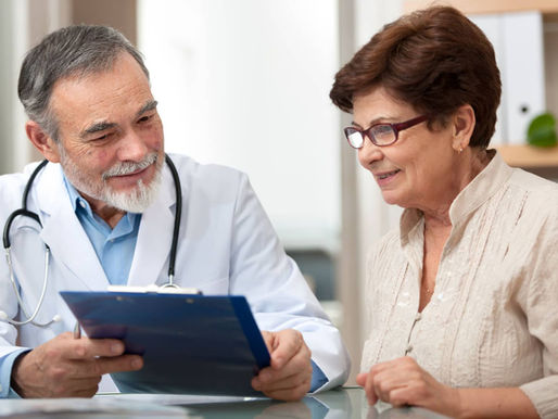 Grey haired doctor talking to an elderly woman