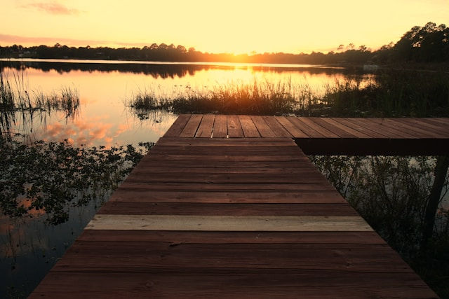 Wooden jetty beside a lake at sunset