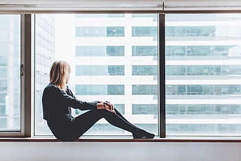 Woman sitting on a window sill, looking out