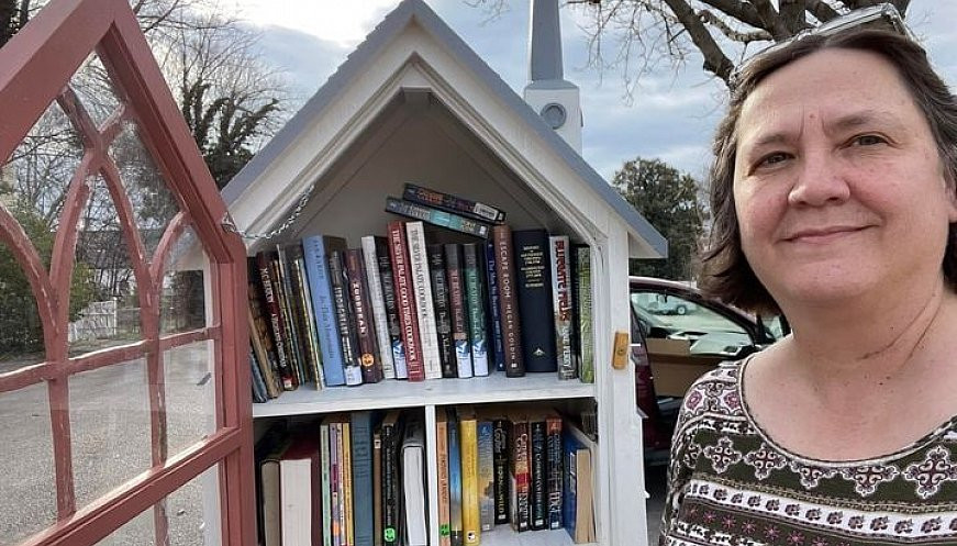 Jennifer Williams standing in front of her portable libraries, containing about 50 books