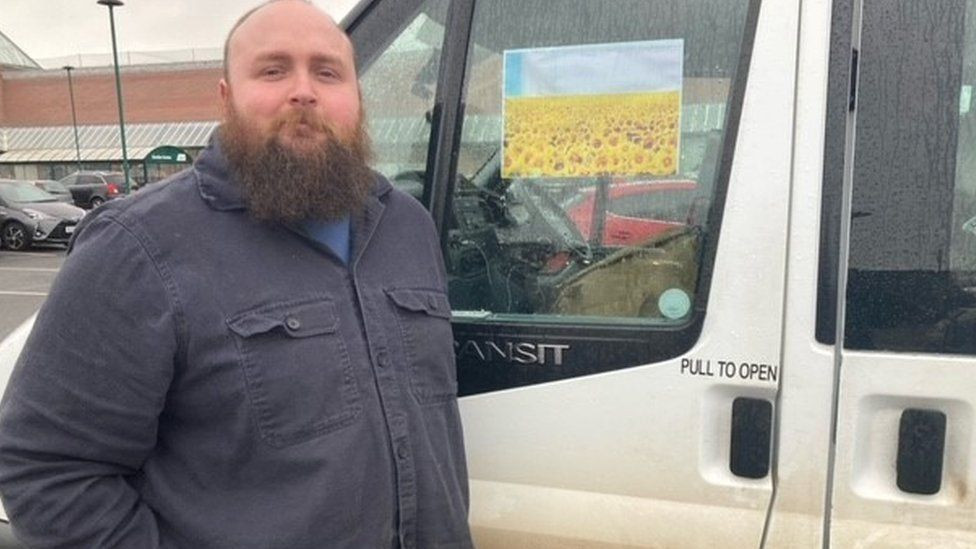 A bearded Tom Littledyke standing in front of his large white van.