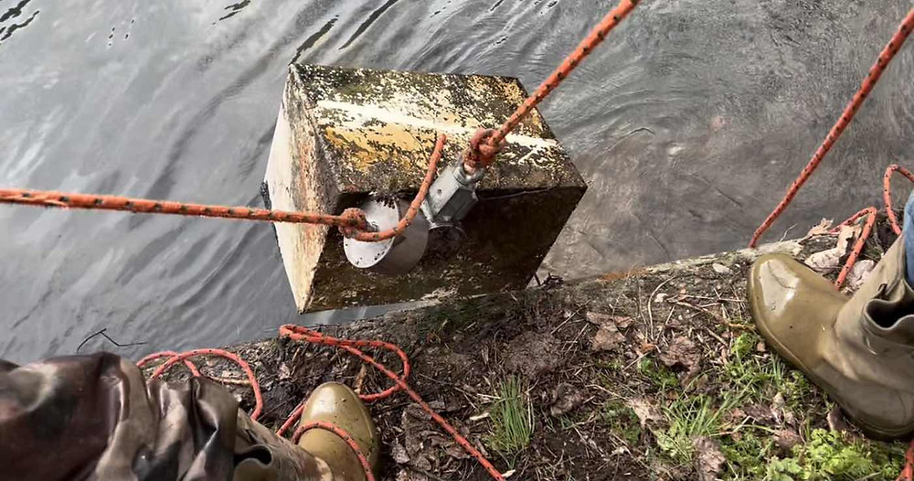Sturdy ropes hauling a rusty safe out of a river