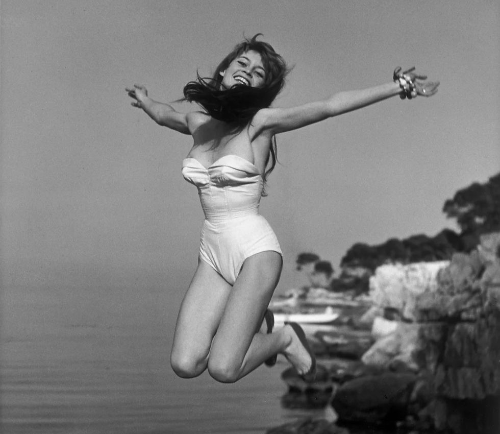 Brigitte Bardot in 1955 wearing a bikini and leaping in the air