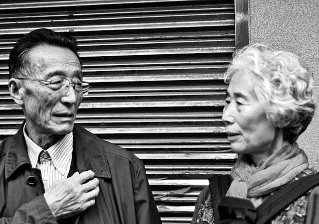 An elderly Japanese couple holding hands and smiling