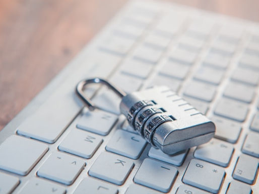 Chrome padlock lying on a white computer keyboard