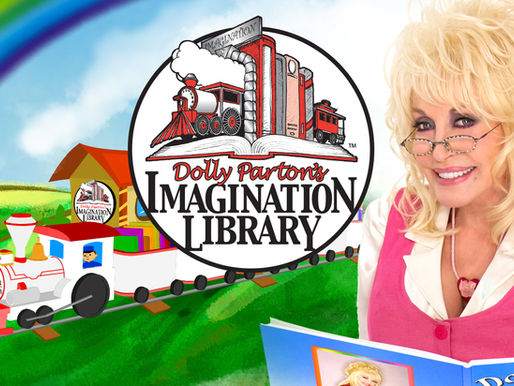 Dolly Parton wearing a pink cardigan, reading a children's book from her 'Imagination Library'
