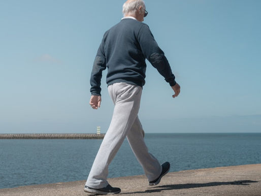 Old man walking briskly along a seafront pier