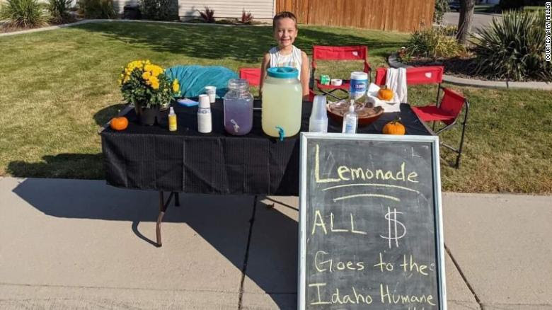 Ben Miller proudly standing behind his lemonade stand on the sidewalk