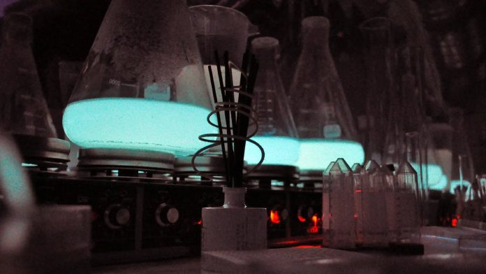 Three glass vials filled with blue glowing bioluminescent liquid