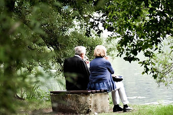 Old couple sitting on a park bench beside a lake