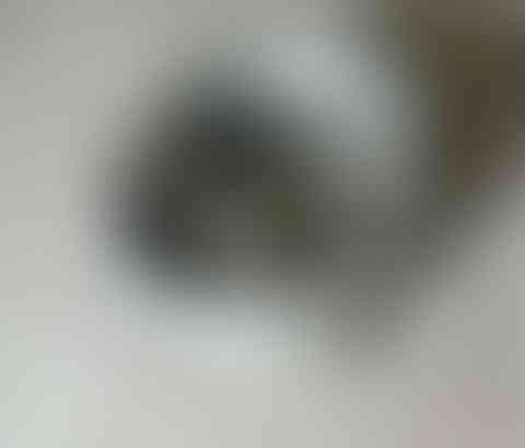 A tightly coiled stainless steel pipe on a concrete floor.