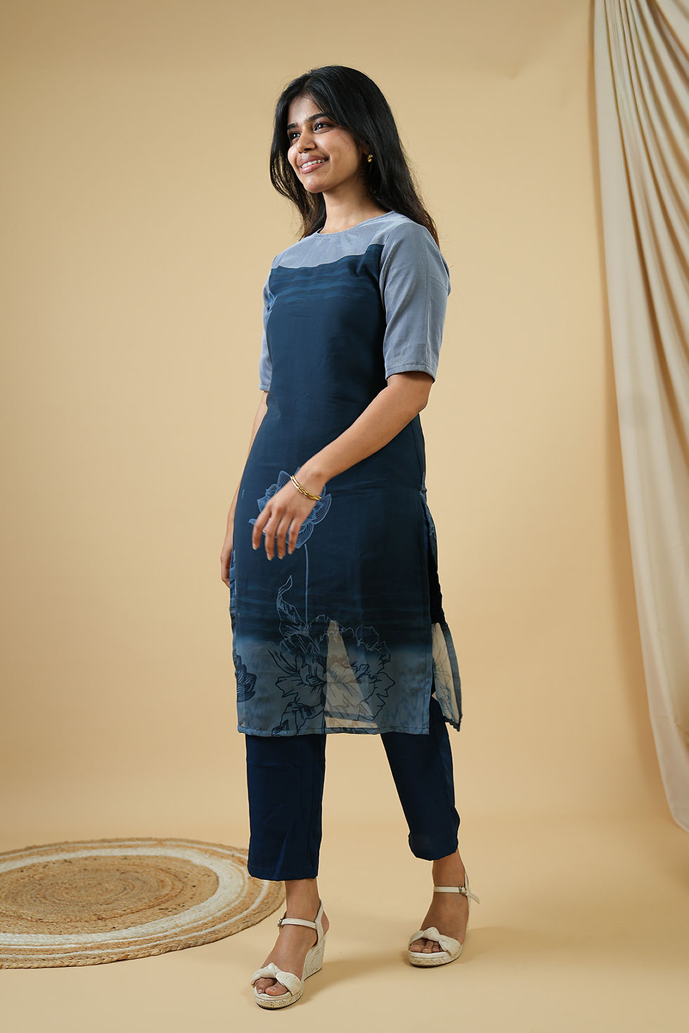 Smiling woman wears patterned indigo blue tunic and matching pants.