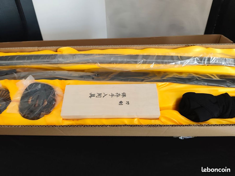 Miniature : Plan moyen du sabre katana noir et de son kit de nettoyage disposés soigneusement dans le coffret cadeau jaune.