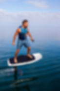 Man riding an electric hydrofoil foil board on a lake with a life jacket_edited.jpg