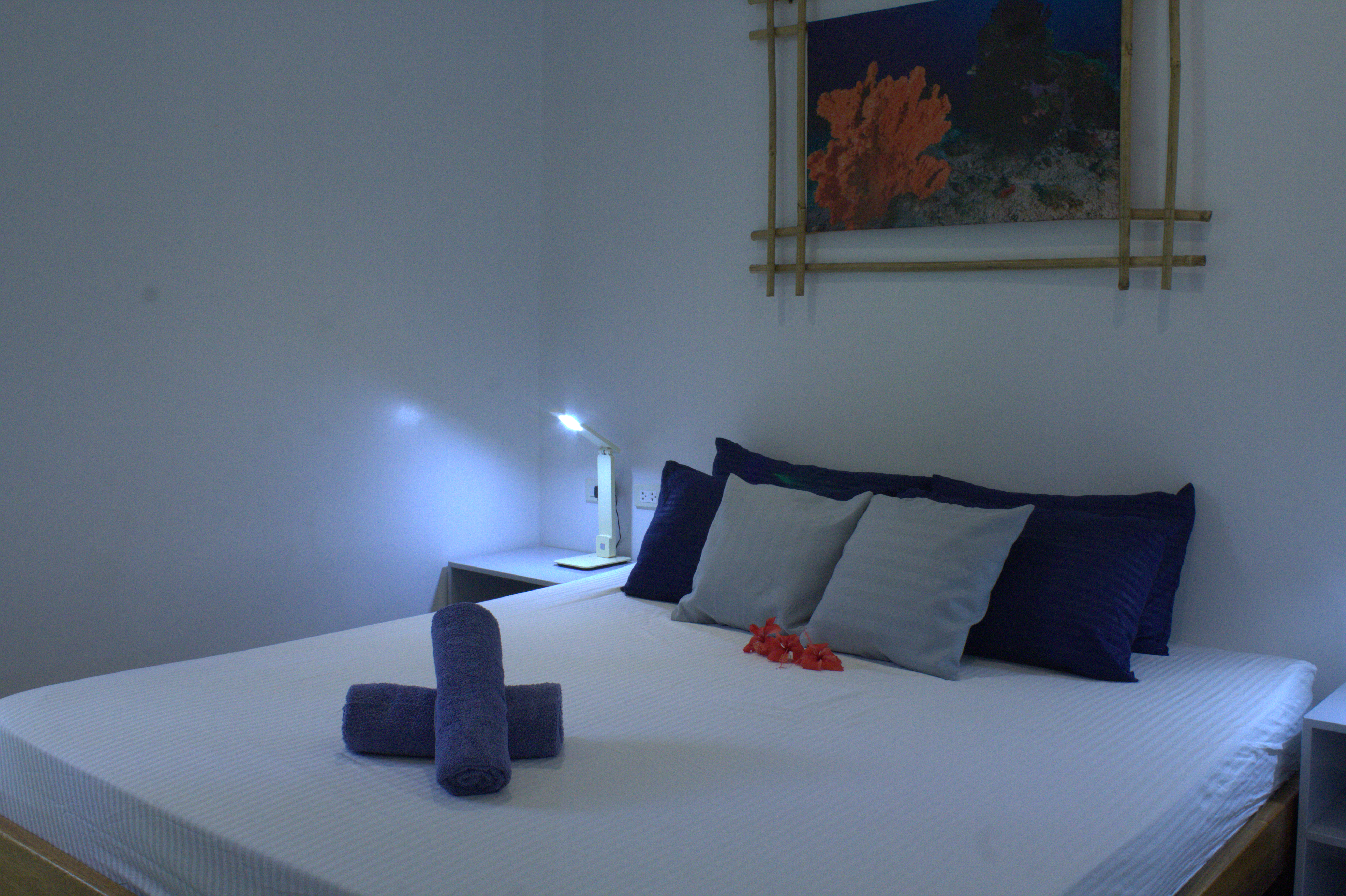 Bright guest room with white bedding and folded towels at Pili Beach Resort