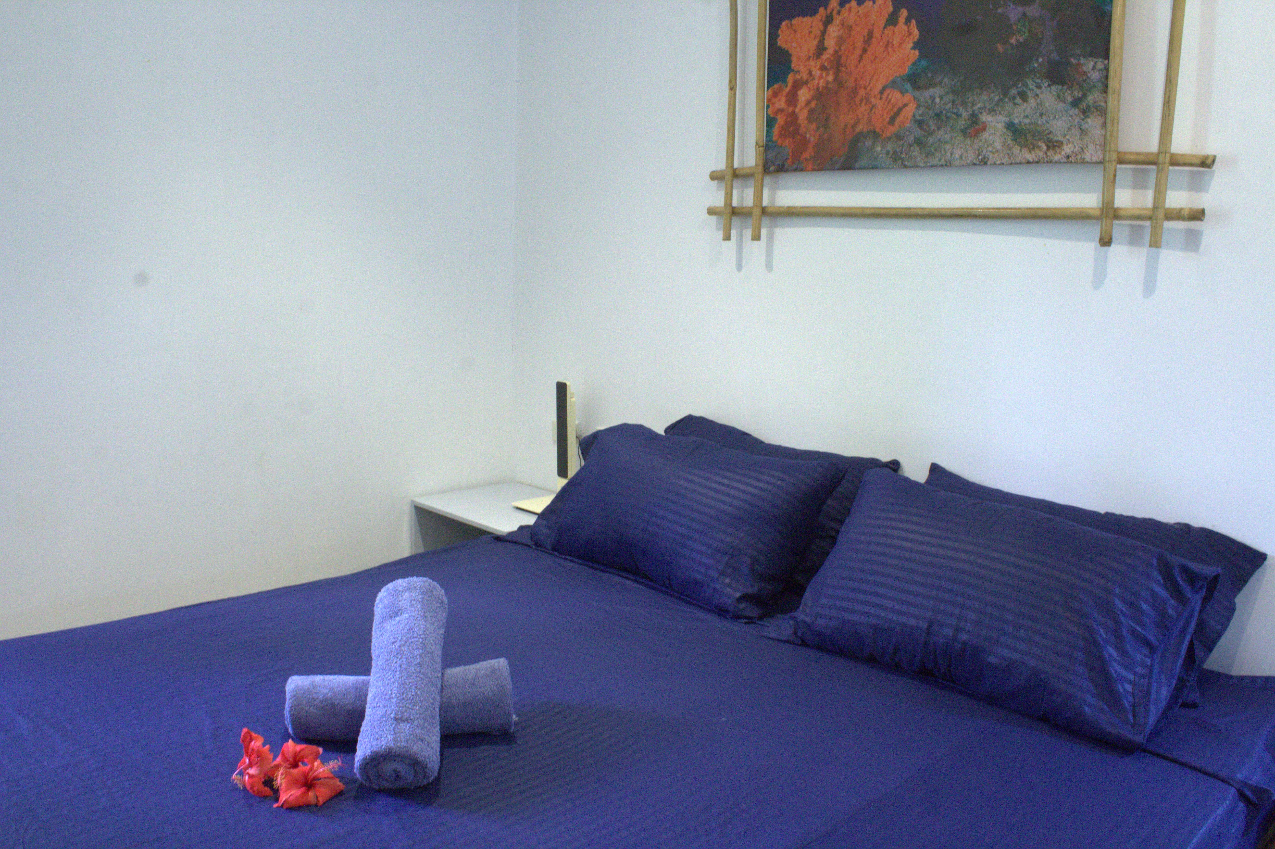 Guest room with navy bedding and folded towels at Pili Beach Resort