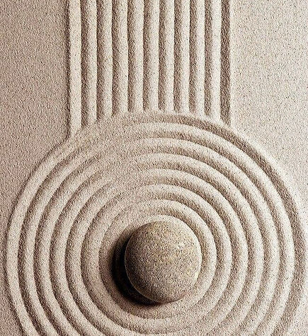 Smooth stacked stones in soft rippled sand symbolizing calm, support, and nurturing energy