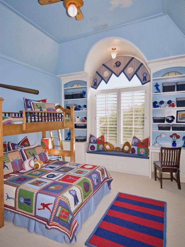 Child’s sports-themed bedroom with a wooden bunk bed, arched window with a built-in seat, and sports-decorated shelves.
