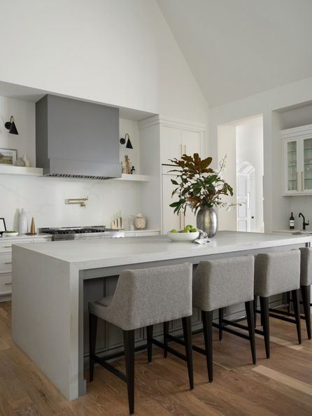 Modern kitchen with a gray island, bar stools, and a range hood. Interior Design project in the Serenbe community in Chattahoochee Hills, Georgia.