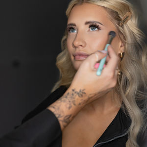 Woman having makeup applied with a brush.